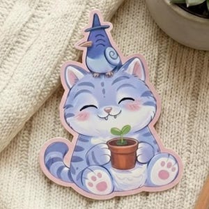 Könnte beinhalten: Ein Aufkleber mit einer Cartoon-Katze mit blauen Streifen, einem Vogel auf dem Kopf und einer kleinen Pflanze in einem Topf. Die Katze lächelt und hat rosa Akzente. Ein Bleistift und eine Sukkulentenpflanze in einem Topf sind ebenfalls zu sehen.