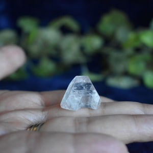 Puede incluir: Un cristal transparente y facetado en forma de pir&aacute;mide, descansando sobre una mano.