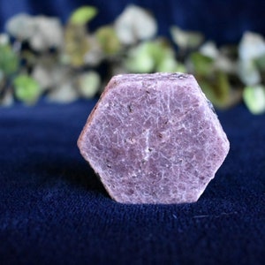 May include: A large, hexagonal, pink ruby crystal with a rough, textured surface.