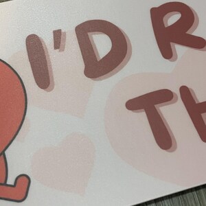 May include: A light pink card with the words "I'D RATHER" in a brown, playful font. The background features light pink hearts. The card has a matte finish.