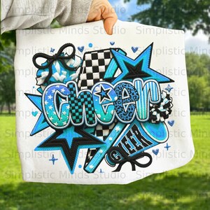 May include: White fabric with a vibrant "CHEER" design in shades of blue, black, and teal. The design includes stars, a megaphone, and a bow, with a mix of patterns like stripes, polka dots, and leopard print. The word "CHEER" is the focal point.