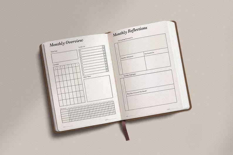 May include: Open journal with brown cover and white pages. The left page is labeled "Monthly Overview" and includes sections for goals, a calendar, and notes. The right page is labeled "Monthly Reflections" with prompts for reflection.