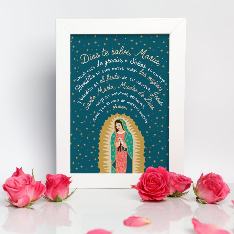Puede incluir: Una impresi&oacute;n enmarcada con un fondo azul verdoso y estrellas doradas. La impresi&oacute;n presenta una ilustraci&oacute;n colorida de la Virgen Mar&iacute;a con el texto "Dios te salve, Mar&iacute;a" en espa&ntilde;ol. El texto est&aacute; escrito en una escritura decorativa.