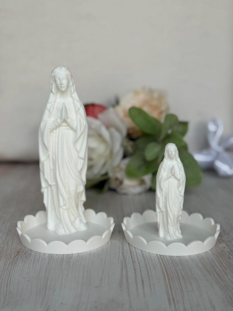 Peut inclure: Deux figurines blanches mates de la Vierge Marie en position de pri&egrave;re, chacune pos&eacute;e sur un plateau circulaire assorti &agrave; bord festonn&eacute;. Les figurines sont r&eacute;alis&eacute;es dans un mat&eacute;riau blanc opaque et solide, avec des robes drap&eacute;es.