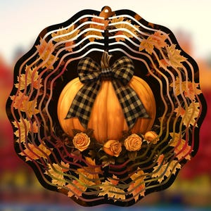 May include: A metal wind spinner featuring a pumpkin design. The pumpkin is orange with a black and white checked bow. The wind spinner is surrounded by autumn leaves.
