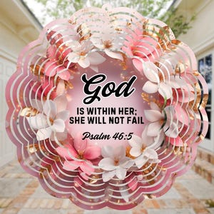 May include: Pink and gold wind spinner with a floral design and the text "God is within her; she will not fail. Psalm 46:5"