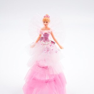 Könnte beinhalten: Eine rosa und weiße Feenpuppe mit einem Tüllkleid und einer Krone. Die Puppe hat blonde Haare und einen glitzernden Oberkörper.