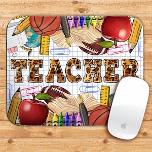 Op de afbeelding: Een witte muismat met een rasterpatroon en het woord "TEACHER" in luipaardprint in het midden. De achtergrond is gevuld met schoolbenodigdheden zoals potloden, kleurpotloden, appels, een basketbal, een voetbal en een liniaal.