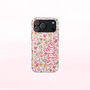 May include: A phone case with a light pink background featuring a pattern of medical-themed illustrations, including pills, bandages, stethoscopes, and syringes. The name "Sophie" is written in a cursive font.