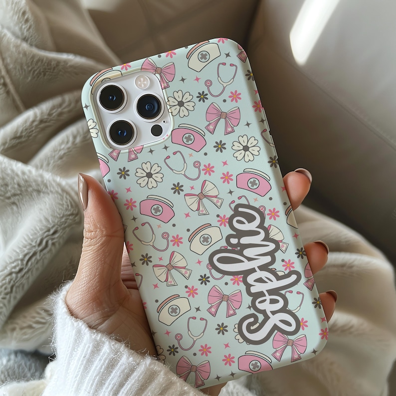 May include: A light blue phone case with a pattern of pink bows, flowers, nurse hats, and stethoscopes. The name "Sophie" is written in a cursive font on the case.