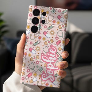 May include: A phone case with a repeating pattern of medical-themed illustrations, including stethoscopes, pills, syringes, and bandages, in pastel colors. The name "Sophie" is written in a cursive font. The case has a pink background.