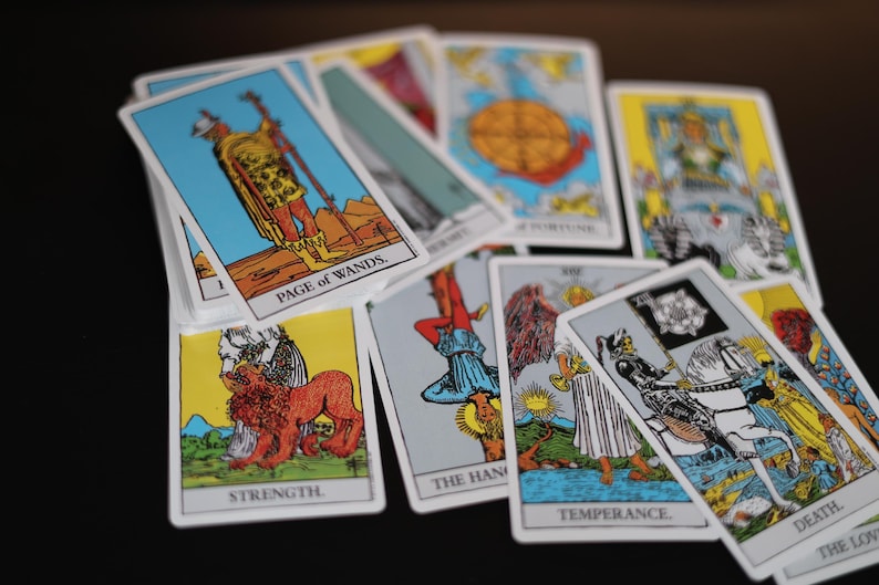 May include: A collection of tarot cards, featuring illustrations and titles such as "Page of Wands," "Strength," and "Death." The cards have white borders and colorful imagery, including figures, symbols, and scenes.