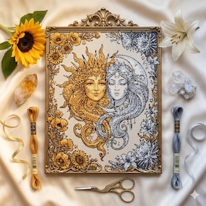 May include: A framed cross-stitch featuring the sun and moon, surrounded by flowers. The artwork uses gold and silver thread, set in a gold frame. Additional items include a sunflower, crystals, embroidery thread, and gold scissors.