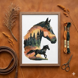 Könnte beinhalten: Ein gerahmtes Kreuzstich-Stickbild mit der Silhouette eines Pferdekopfes, gefüllt mit einer Waldlandschaft bei Sonnenuntergang und einem kleineren schwarzen Pferd, das darunter läuft, auf weißem Rasterstoff in einem hellbraunen Holzrahmen.