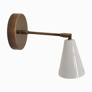 May include: A wall-mounted lamp with a circular brass base and a long, straight arm. The lamp features a white, cone-shaped shade. The design is minimalist and modern, suitable for various interior styles.