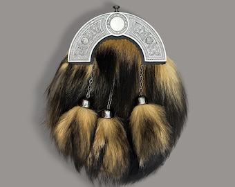 Puede incluir: Un sporran escocés tradicional con un cantle plateado con nudos celtas. El cuerpo del sporran es de piel en tonos negros, marrones y beige, con tres borlas de piel a juego colgando de capuchones y cadenas plateadas.