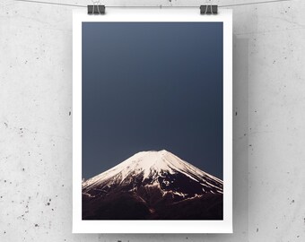 Può includere: Una fotografia del Monte Fuji, una montagna innevata, contro un cielo blu scuro.