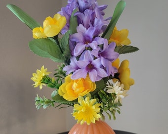 Mini Bouquet: A beautiful blend of mini yellow roses, orange rose buds, lilac hyacinths, and daisies, and foliage. Retro orange glass vase