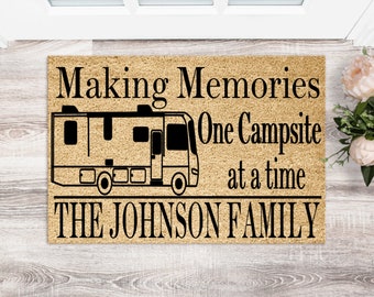 May include: A brown doormat with the text "Making Memories One Campsite at a time THE JOHNSON FAMILY" and a black silhouette of a recreational vehicle.