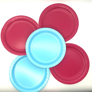 May include: Five paper plates arranged in a circle. Two plates are light blue, and three are a deep red. The plates have a slightly raised rim and a smooth centre. The plates are on a white background.