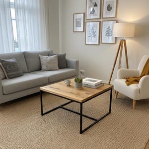 Könnte beinhalten: Wohnzimmer mit grauem Sofa, dekorativen Kissen und einem Couchtisch aus Holz mit schwarzem Metallrahmen. An der Wand hängen gerahmte Kunstwerke, und eine Stehlampe sorgt für Beleuchtung. Ein beiger Teppich bedeckt den Boden.