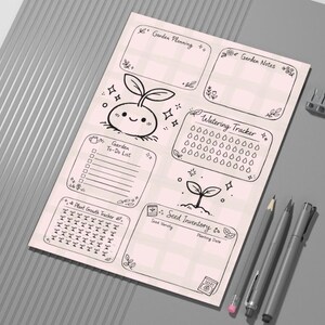 Può includere: Un foglio di pianificazione del giardino rosa chiaro con disegni a tratto nero. Il foglio include sezioni per la pianificazione del giardino, note, una lista di cose da fare, un tracker di irrigazione, l'inventario dei semi e un tracker della crescita delle piante. Una matita, una penna e una matita meccanica sono a destra.