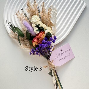 May include: A dried flower bouquet with a variety of textures and colors, including purple, orange, white, and beige. A pink tag tied to the bouquet reads "Will you be my bridesmaid." The text "Style 3" is also visible.