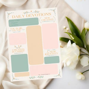 Könnte beinhalten: Ein druckbares "Daily Devotions"-Blatt mit Abschnitten für Notizen, Verse und Daten. Das Design zeigt pastellfarbene rosa, grüne und beige Blöcke mit floralen Akzenten und Bibelversen. Der Text enthält "Daily Devotions", "New Creation" und "A New Identity".