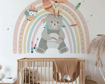 May include: A colorful rainbow wall decal with a bear, fox, and owl wearing headdresses. The animals are on a rainbow with feathers and arrows. The decal is on a white wall above a wooden crib.