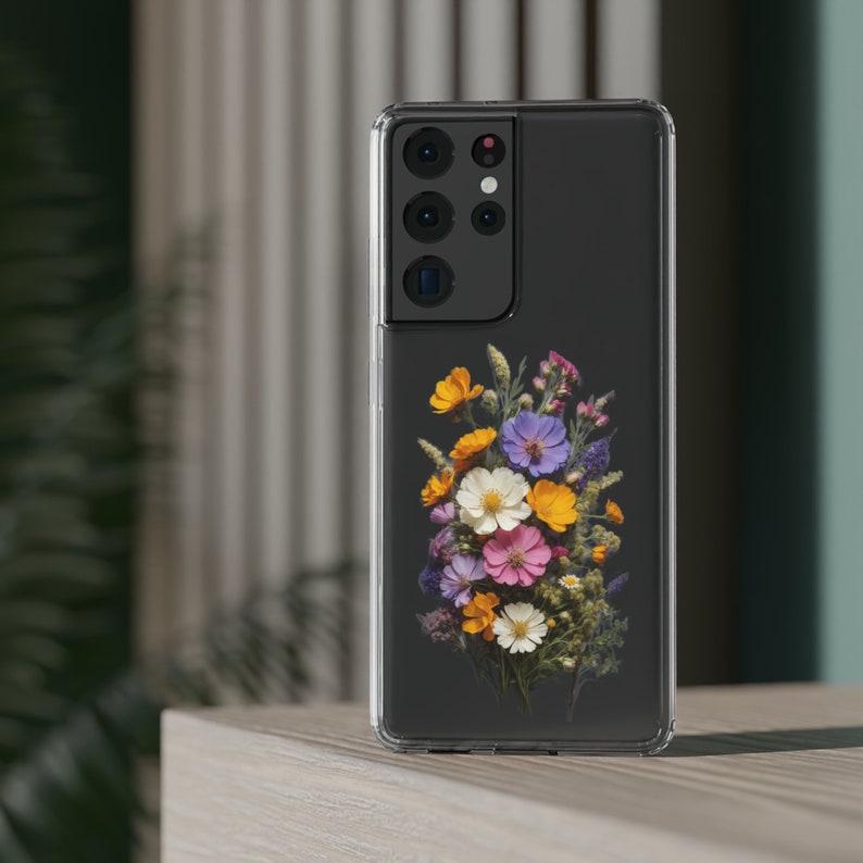 May include: A clear phone case with a floral design. The case is black and has a raised camera bump. The flowers are pressed and colorful, including yellow, orange, pink, purple, and white.