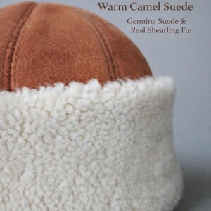May include: A warm camel suede hat with a genuine suede crown and a real shearling fur brim. The hat is a light brown color with a white fur brim. The text "Warm Camel Suede" and "Genuine Suede & Real Shearling Fur" is visible.
