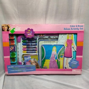 May include: A pink and blue Barbie Colour & Erase Deluxe Activity Set with 16 activities. The set includes a colour and erase art desk, colour and erase markers, colour and erase stamps, and an eraser. The box shows a Barbie doll wearing a pink dress and a Barbie doll wearing a purple dress.