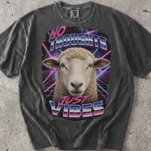 May include: A charcoal gray short-sleeve t-shirt featuring a graphic of a sheep's head centered within a neon-colored grid and lightning background. The text "NO THOUGHTS" appears above the sheep, and "JUST VIBES" is printed below in a retro font.
