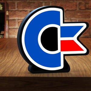 May include: A three-dimensional sign featuring a large blue letter C with a white outline and a black centre. To the right of the C is a horizontal rectangular shape divided into a blue top section and a red bottom section, all outlined in white.