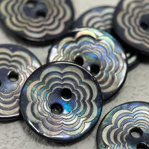 May include: A collection of round, dark iridescent buttons featuring a central two-hole design. Each button displays a repeating scalloped pattern etched into the surface, revealing shimmering blue and purple tones characteristic of shell material.