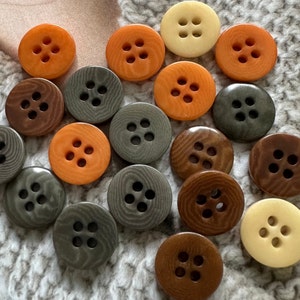 May include: Assortment of colorful buttons with four, five, and six holes. The buttons are in various shades of brown, orange, and gray.