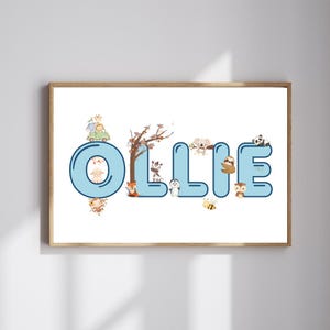 Op de afbeelding: Een ingelijste print met de naam "Ollie" in grote, blauwe bubbelletters. De letters zijn versierd met verschillende cartoon dieren, waaronder een aap, een schaap, een vos, een zebra, een pinguïn, een koala, een luiaard, een uil, een panda en een bij. De achtergrond is wit.