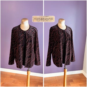 Könnte beinhalten: Schwarze Jacke mit rotem und weißem Wellenmuster, auf einer Schaufensterpuppe präsentiert. Die Jacke hat lange Ärmel und einen runden Ausschnitt. Das Wort "notations" ist auf einem rechteckigen Etikett über der Jacke aufgedruckt.