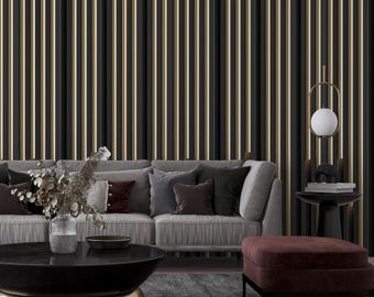 May include: A gray sofa with burgundy and gray throw pillows sits in front of a wall with vertical gold and black stripes. A black coffee table with a round top sits in front of the sofa. A burgundy ottoman sits in front of the coffee table. A gold pendant light with a white globe hangs from the ceiling.