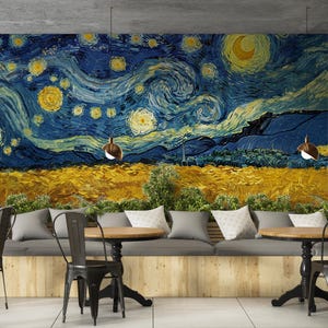 May include: A wall mural featuring a swirling night sky with bright yellow stars and a crescent moon above a golden wheat field. Below the mural is a long grey bench with white pillows, two round wooden tables, and black metal chairs.
