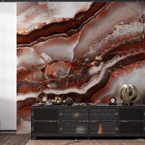 May include: A black metal sideboard with mesh cabinet doors sits against a wall featuring a large-scale mural of brown, white, and deep red agate stone patterns. Decorative objects including a clock and metallic sculptures rest on the top surface.
