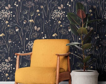 May include: A mustard yellow armchair with wooden arms and legs sits in front of a dark blue wall with a floral pattern. The pattern features dried flowers and butterflies in shades of beige and white.
