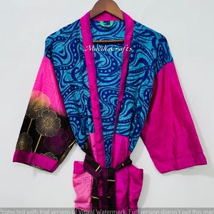 May include: A vibrant, patterned kimono robe in shades of blue, pink, and black. The robe features a blue and white swirl design on the front and back, with pink accents and sleeves. The sleeves have a floral pattern. The text "MadihaCrafts" is visible.