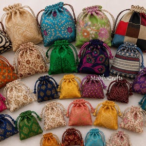 May include: A collection of small drawstring pouches in various colors and patterns, including floral, paisley, geometric, and solid designs. Each fabric bag features a matching cord closure. The text MadihaCrafts is visible in the center.