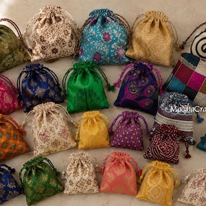 Può includere: Una collezione di piccole borse con coulisse in vari colori e motivi, inclusi disegni floreali, paisley e geometrici. Le borse in tessuto presentano chiusure a cordoncino abbinate e il testo MadihaCrafts è visibile su una delle borse.