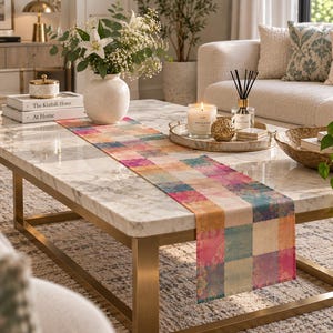 May include: A rectangular table runner featuring a patchwork design of multicolored squares in shades of pink, orange, blue, and cream. Each square displays a subtle, intricate floral pattern, creating a vibrant and textured appearance.