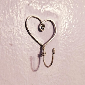 May include: A silver heart-shaped hook with a small silver bead at the top of the heart.