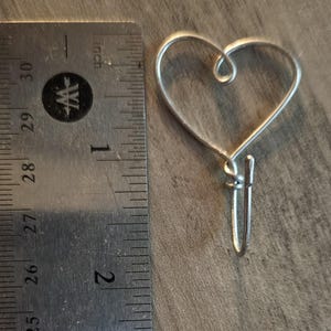 Puede incluir: Un adorno de coraz&oacute;n de alambre plateado con un lazo en la parte inferior para colgar.
