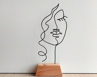 Visage femme fil de fer minimaliste sur socle contemporain abstrait