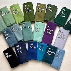 May include: An assortment of folded fabric swatches in various colors, including green, blue, purple, and black. Each swatch is labeled with a color name, such as "seafoam green," "teal blue," and "indigo purple."